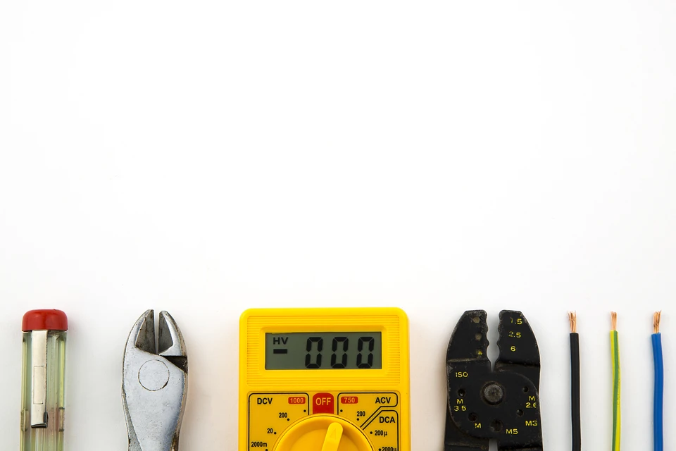 Espace de travail d'électricien sur fond blanc avec outils professionnels alignés